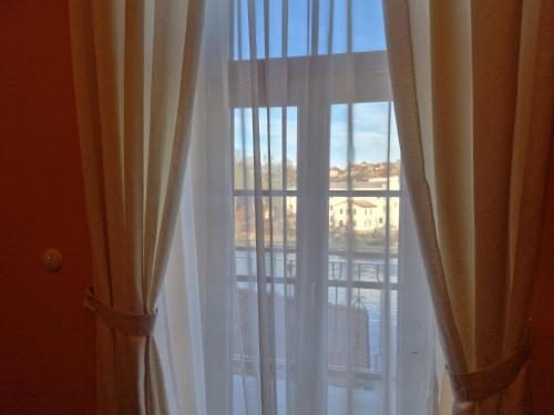 a window with white curtains and a view of a city at ROMANTIK HOTEL ELEONORA in Tábor