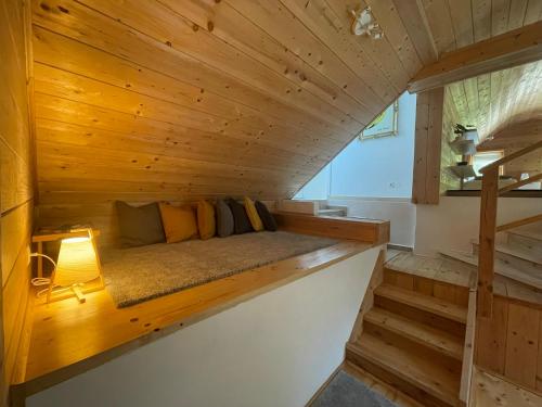 a bed in a cabin with wooden walls and stairs at wundervoll eben - CHALETS & PLÄTZE voller WUNDER - NOTSCHKERL & FEINIS in Waasen