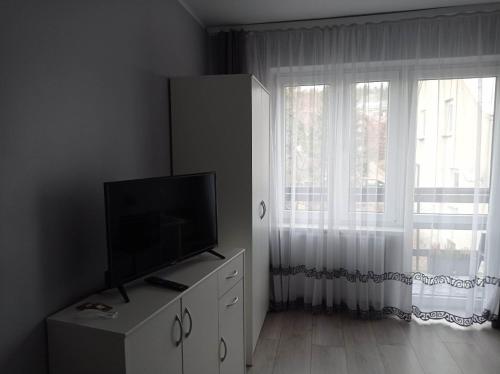 een woonkamer met een televisie op een dressoir met een raam bij Dom Gościnny "Zawiśle" in Włocławek