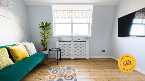 ein Wohnzimmer mit einem grünen Sofa und einem Fenster in der Unterkunft Luxurious 1-Bedroom Apartment in Kensington in London
