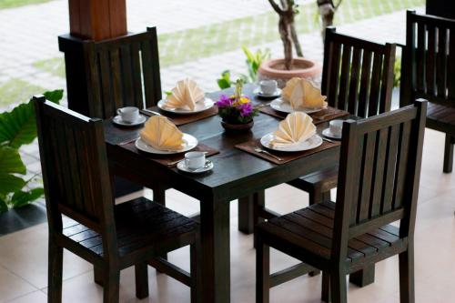 a wooden table with chairs and plates of food on it at Gita Maha Ubud Hotel by Mahaputra-CHSE Certified in Ubud