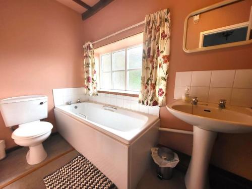 a bathroom with a tub and a toilet and a sink at The Old Dairy in rural sea side location in Norwich