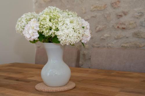 a white vase with flowers in it on a table at Gite Oliveira's in Ury