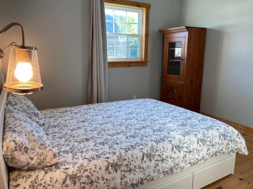 a bedroom with a bed with a lamp and a window at Magnifique centenaire rénovée, air climatisé, arcade, 3 chambres fermées in Austin