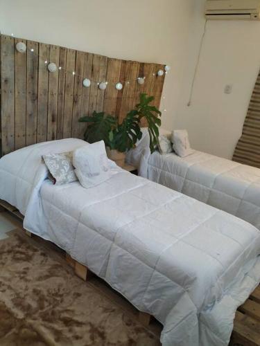 2 camas con sábanas blancas en una habitación en eco veggie en Esperanza