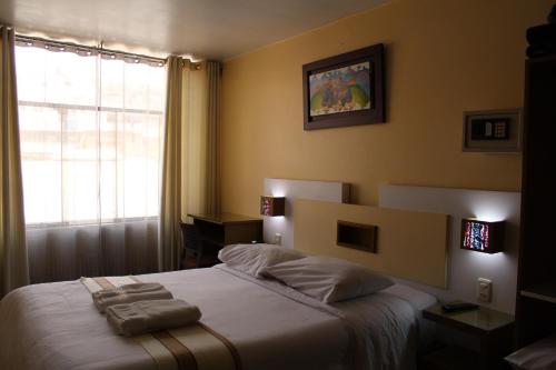 a bedroom with a bed with two towels on it at Kaaro Hotel Puno in Puno