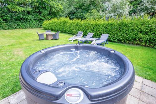 a large jacuzzi in a yard with chairs and a table at The island life texel met jacuzzi in De Koog