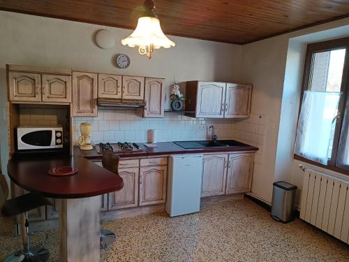 une cuisine avec des armoires en bois et une table à l'intérieur dans l'établissement Joyeuse appart mas des chênes, à Joyeuse