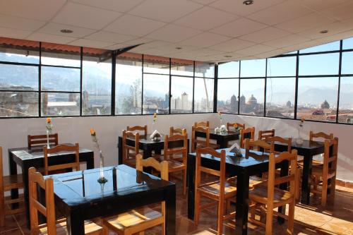 a restaurant with tables and chairs and large windows at KAARO HOUSE CUSCO in Cusco