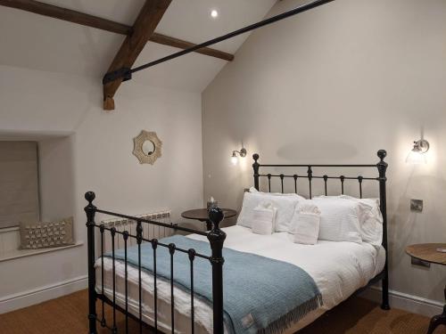 a bedroom with a black bed with white pillows at Brook Cottage Askrigg in Askrigg