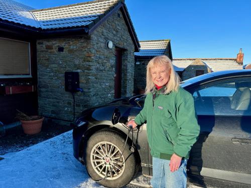 a woman is standing in front of a car at Buxa Farm Chalets in Orphir