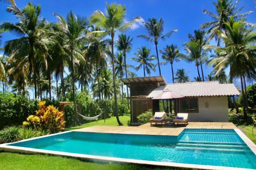 a villa with a swimming pool and palm trees at Hygge Residence - Barra Grande - Península de Maraú in Marau