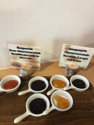 a table topped with bowls of preserves and spoons at Alpenspitz Appartements - Garni - B&B in Racines