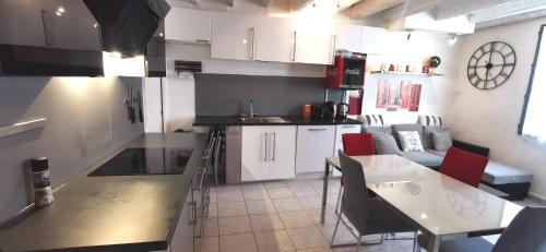 a kitchen with white cabinets and a table with red chairs at Maison de ville centre arles in Arles