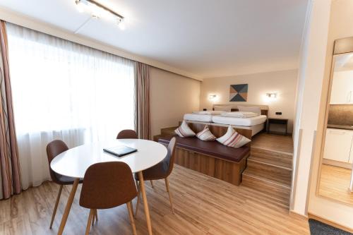 a hotel room with a bed and a table and chairs at Aparthotel Dorfplatzl Garni in Tux
