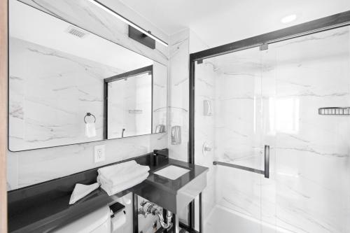 y baño blanco y negro con lavabo y ducha. en Hotel TREMONT Bronx Yankee Stadium, en Bronx