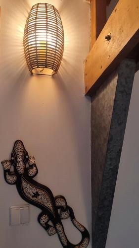 a light on a wall with two snakes on it at Les Gîtes KARMA in Andres