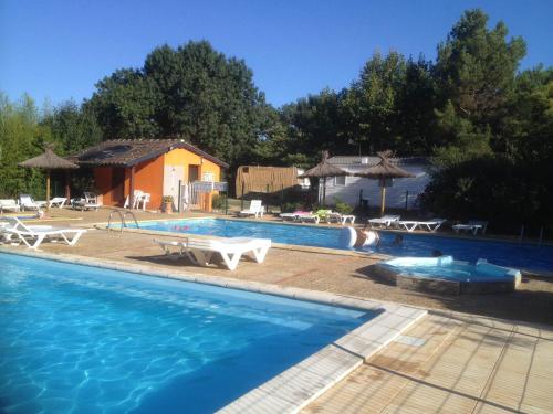 a swimming pool with chairs and a house at Camping de la Chapelette in Saint-Martin-de-Crau