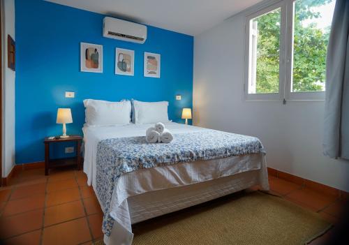Pousada Cocal da Praia في غوارويا: غرفة نوم زرقاء مع سرير مع اثنين من الحيوانات المحشوة عليه