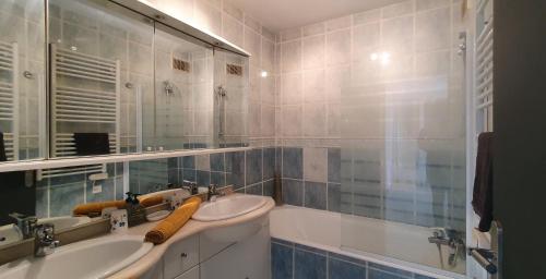 une salle de bain avec deux lavabos, un miroir et une baignoire dans l'établissement Le Silène, à Sainte-Maxime