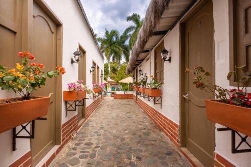 a corridor of buildings with potted plants and flowers at Entre Palmas Casa Hotel in Santa Fe de Antioquia
