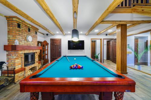 a pool table in a living room with a fireplace at Willa SPAcja in Wężówka