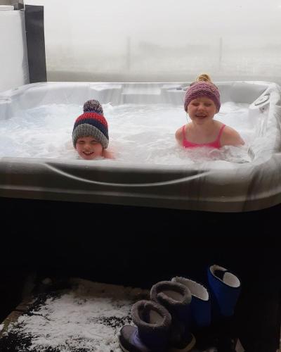 two children wearing hats in a bath tub at Buxa Farm Chalets in Orphir