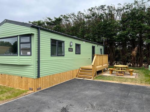 a green tiny house with a picnic table and a bench at Sleepy Hollow Holiday Home in Knaresborough