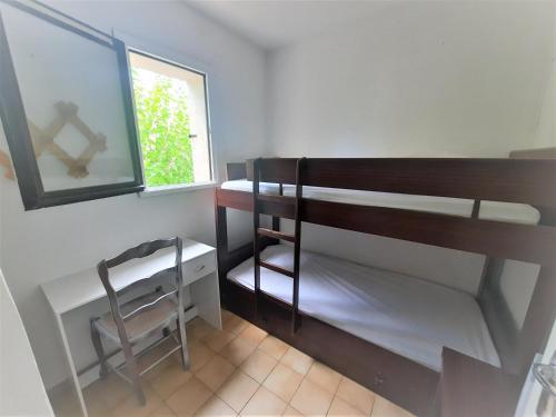 Cette chambre dispose de lits superposés, d'une chaise et d'une fenêtre. dans l'établissement Cavalaire sur mer Appartement T3-160 m plage - 800 m Centre-ville. Park, à Cavalaire-sur-Mer