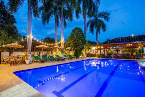 a swimming pool with chairs and palm trees at night at Entre Palmas Casa Hotel in Santa Fe de Antioquia