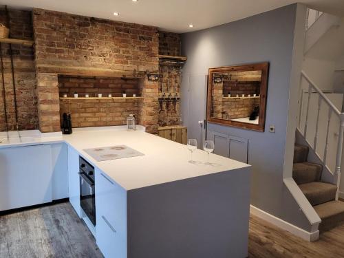 a kitchen with a white counter and a brick wall at Sea View Sandgate in Sandgate
