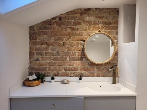 a bathroom with a white sink and a brick wall at Sea View Sandgate in Sandgate
