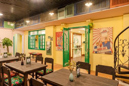 a restaurant with wooden tables and chairs and green doors at Hanoi Retro 80S Homestay in Hanoi