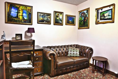 a living room with a leather couch and a desk at A cosy house near the city centre in Glasgow