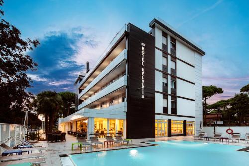 a hotel with a swimming pool in front of a building at Hotel Helvetia in Lignano Sabbiadoro