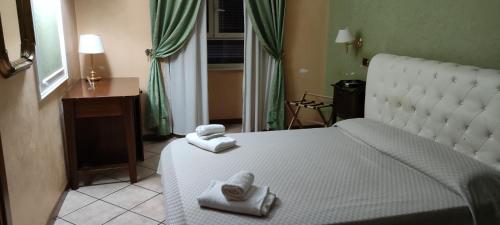 una camera da letto con un letto bianco e asciugamani di Hotel Montreal Uno a Roma