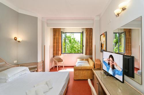 マリーナ・ディ・マッサにあるHotel Nedyのベッドとテレビ付きのホテルルーム