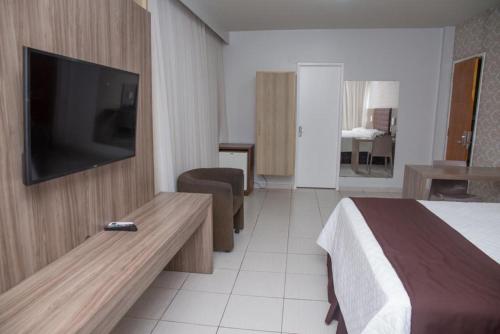 a hotel room with a bed and a flat screen tv at Hotel Village in Garanhuns