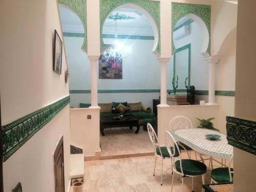 een woonkamer met een trap met een tafel en stoelen bij Dar Tariq 3 suites avec pisicine in Marrakesh