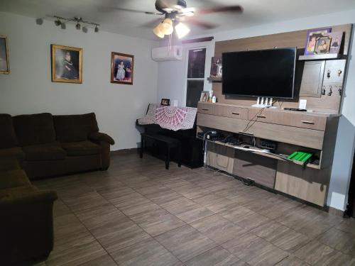 a living room with a couch and a flat screen tv at Habitación en casa particular in Monterrey