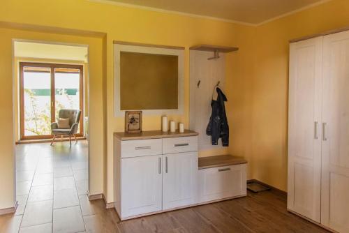 a kitchen with yellow walls and white cabinets at Detvan – getaway in Poľana mountains in Dúbravy