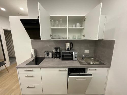 a kitchen with white cabinets and a sink at Deluxe Apartments Messe Flughafen in Leinfelden-Echterdingen