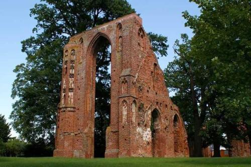 un antiguo edificio de ladrillo en un campo con árboles en Ferienwohnung Urlaub, en Greifswald