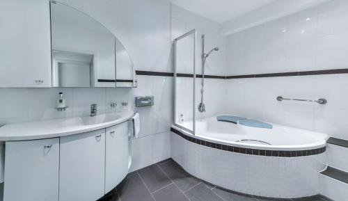 La salle de bains blanche est pourvue d'un lavabo et d'une baignoire. dans l'établissement Boutique Wellnesshotel Landmann, à Steinen