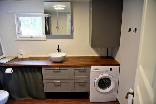 a bathroom with a sink and a washing machine at Lakeside cottage in Lapland with great view in Skaulo