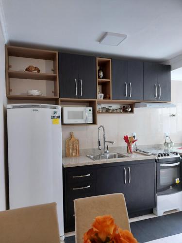 eine Küche mit schwarzen Schränken und einem weißen Kühlschrank in der Unterkunft Apto Confortável próximo ao Consulado Americano in Porto Alegre