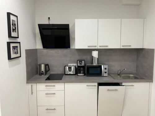 a kitchen with white cabinets and a microwave at Deluxe Apartments Messe Flughafen in Leinfelden-Echterdingen