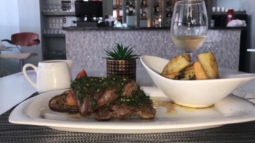 a plate with a steak and a glass of wine at Plaza Coral Hotel in Punta Cana