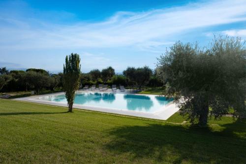 basen na dziedzińcu z krzesłami i drzewami w obiekcie Villa Athena Charme w Manerba del Garda