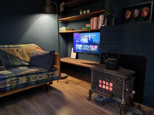 a living room with a couch and a television at Natuurhuis Boscoso met openhaard en elektr.fietsen in Barchem